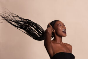 Model Damilola Bolarinde reacts as her braids blow in the wind for OLORI Beauty USA's launch campaign, photographed by Remi Adetiba